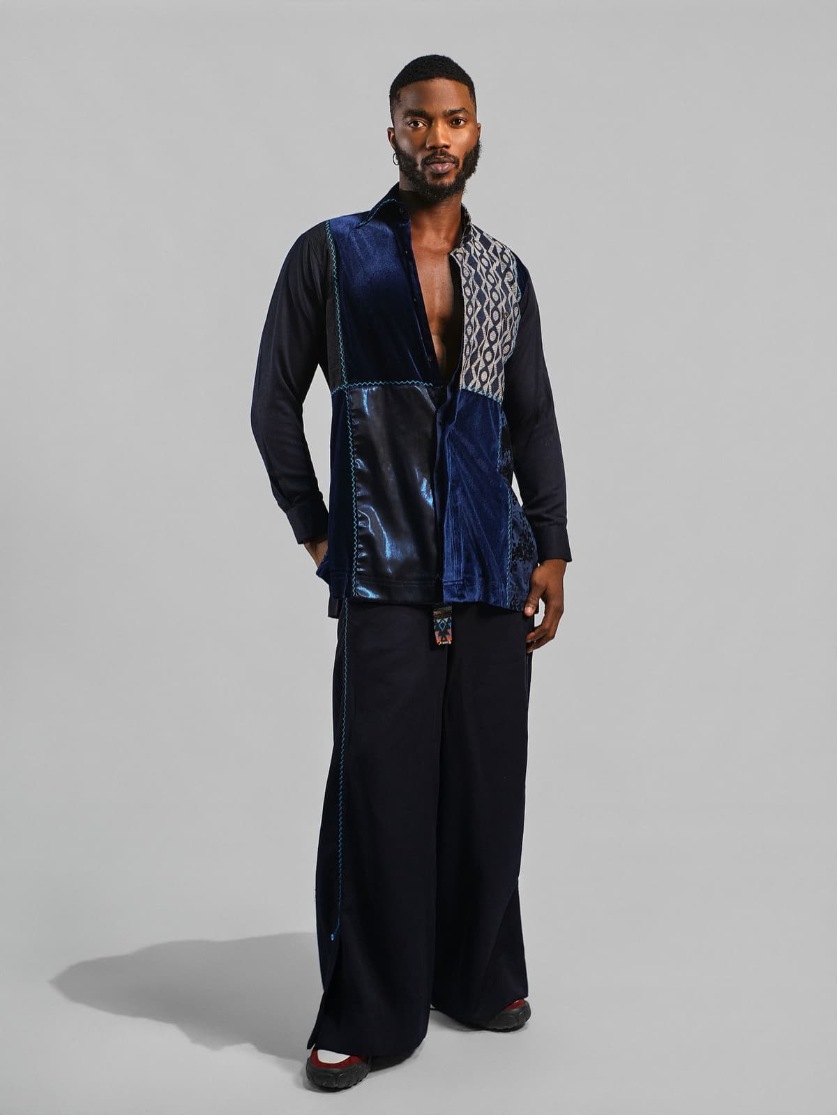 Navy shirt pieced with velvet and a black and white woven panel, over wide navy trousers.