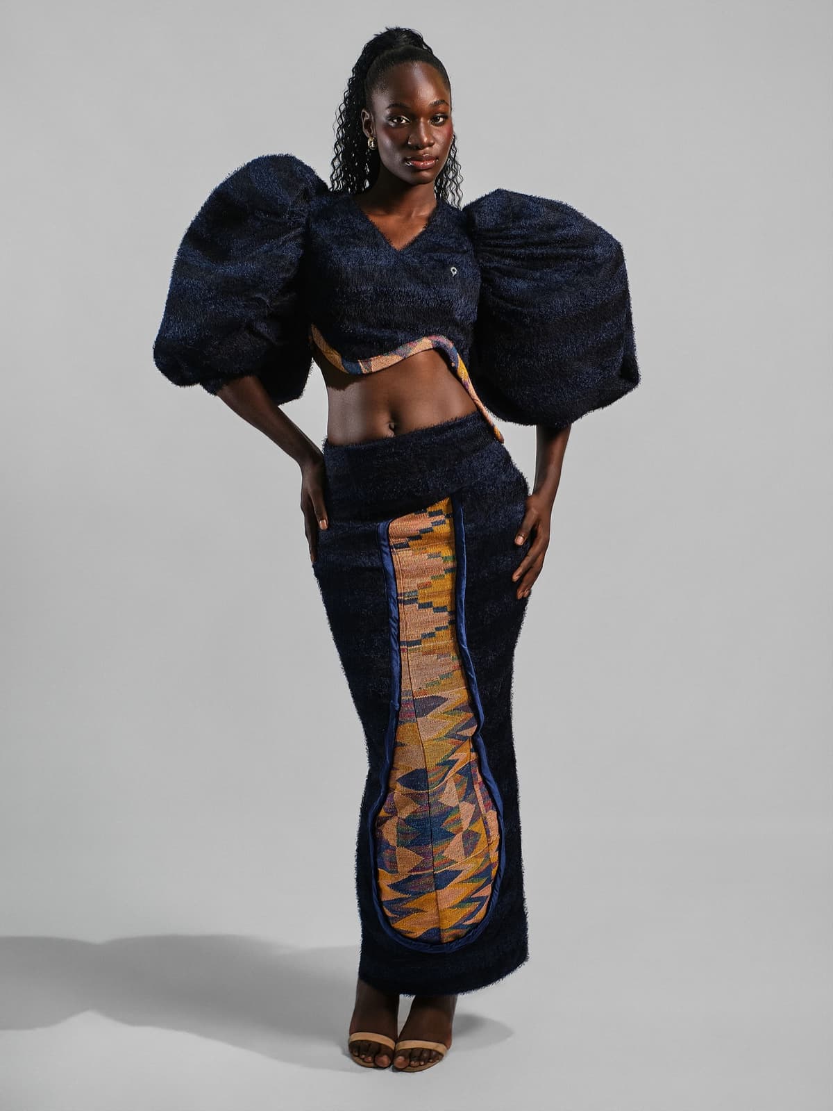 Navy cropped top with sculpted balloon sleeves and a column skirt with an orange woven inset.